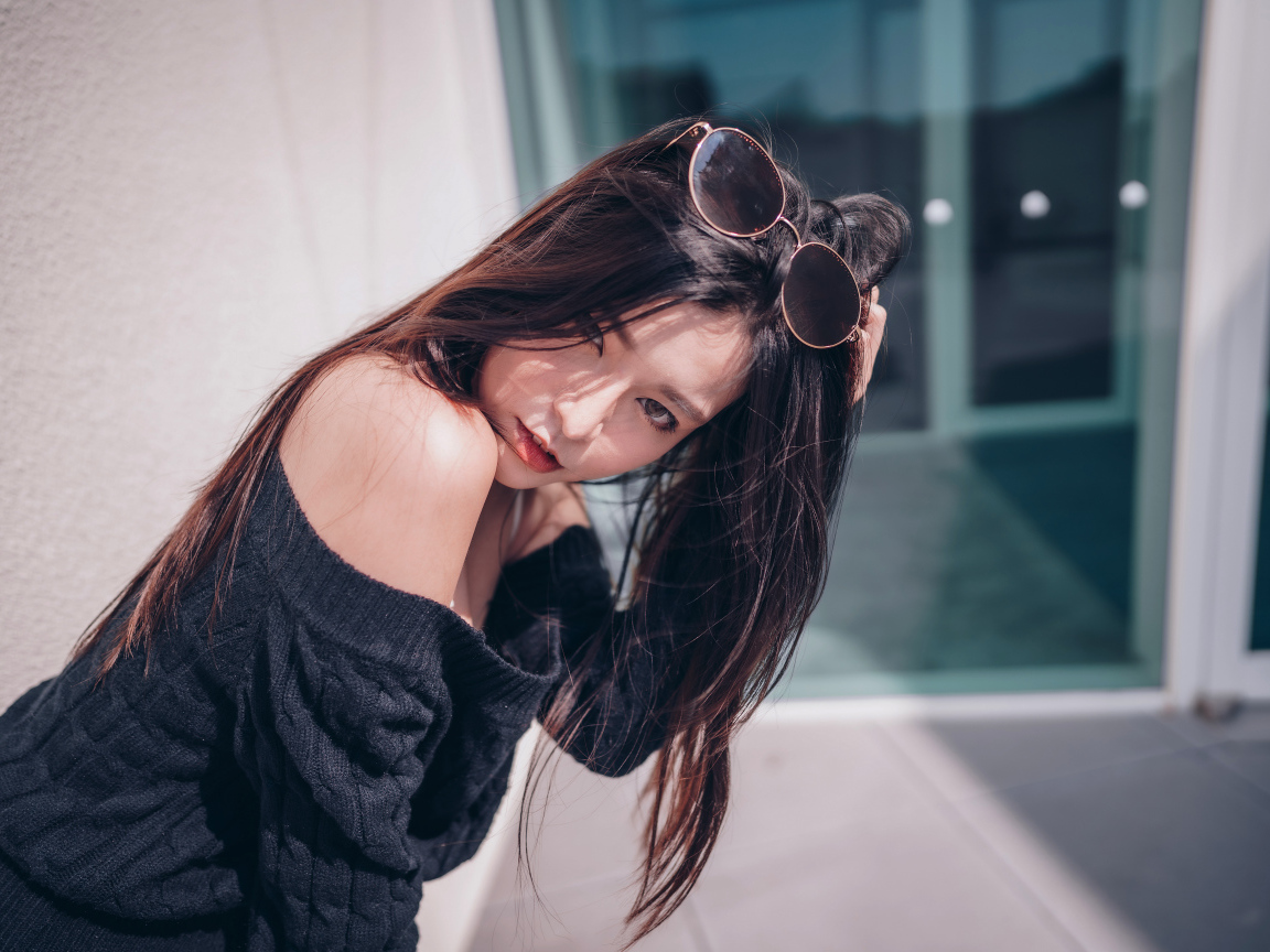 Красивая азиатка в черном свитере с солнечными очками на голове 