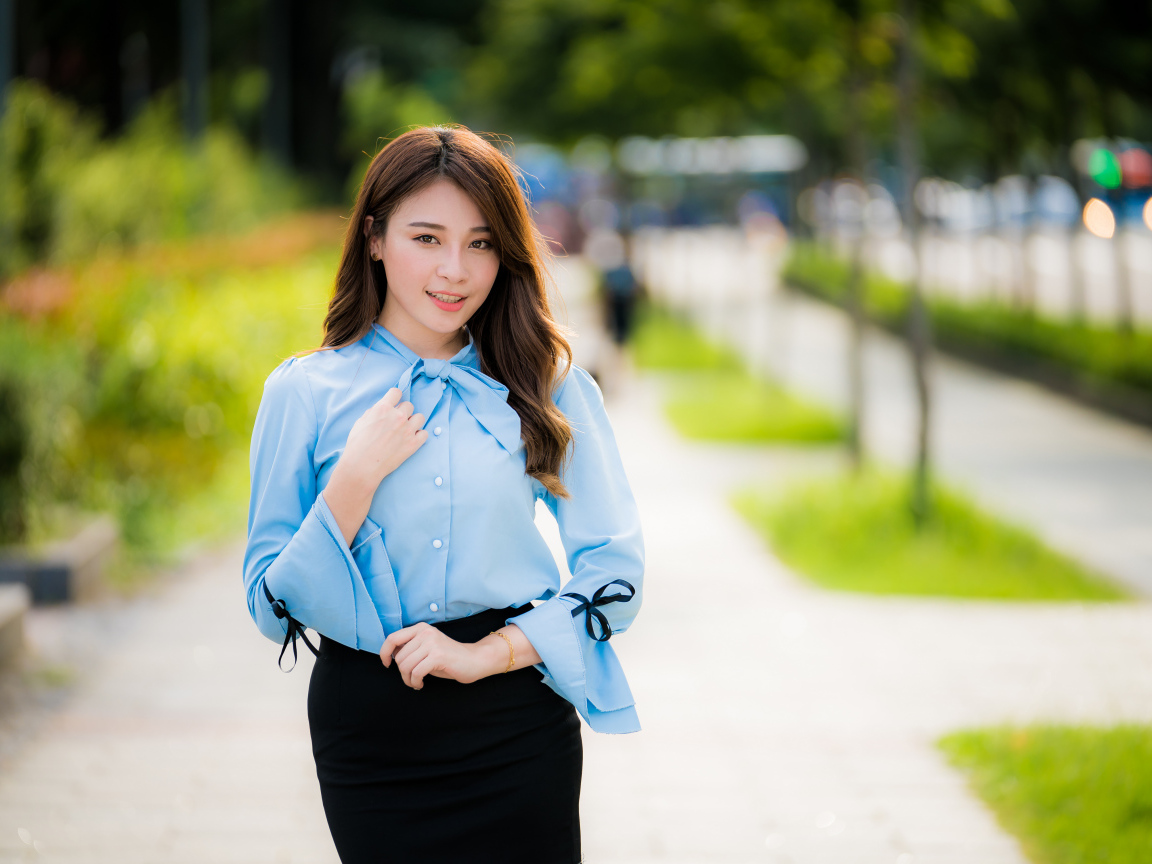 Красивая азиатка в голубой блузке и черной юбке 