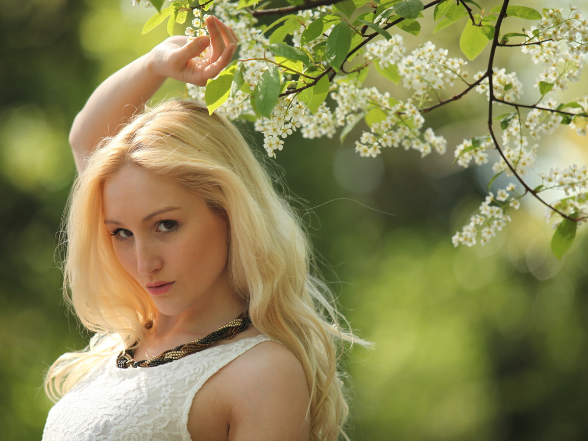 Красивая блондинка у ветки с белыми цветами