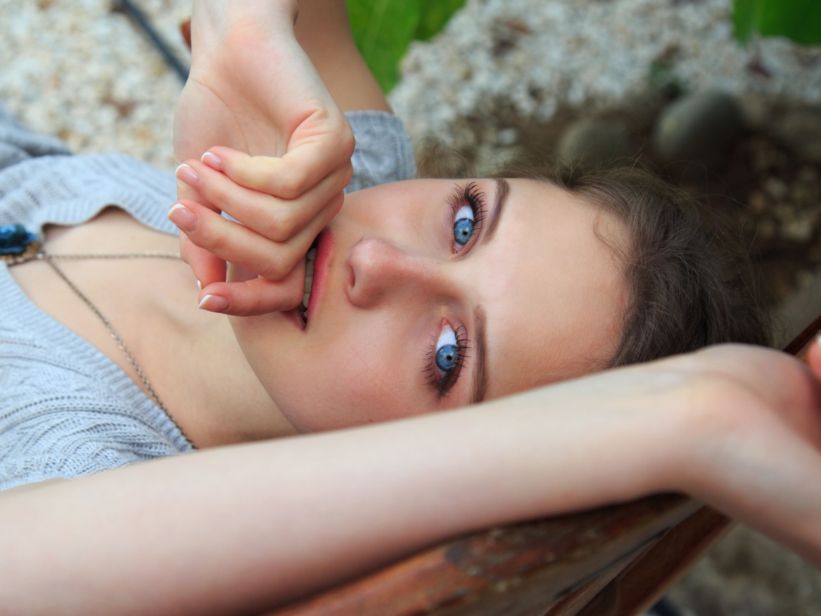 Красивая голубоглазая девушка с рукой у рта