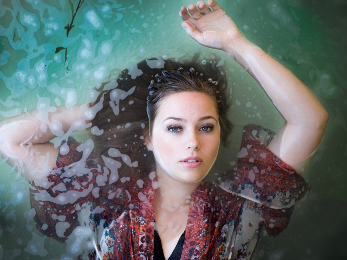 Красивая девушка лежит в одежде в воде 