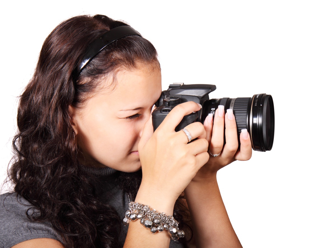 Молодая девушка шатенка с фотоаппаратом в руках на белом фоне