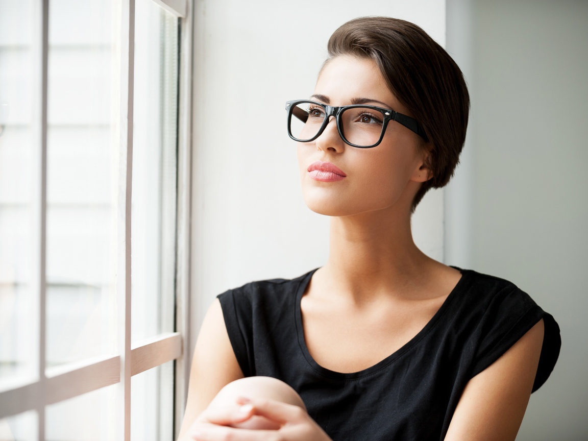 Деловая девушка в очках сидит у окна 