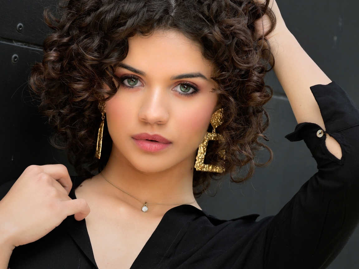 Кудрявая девушка с рукой в волосах в черной рубашке 