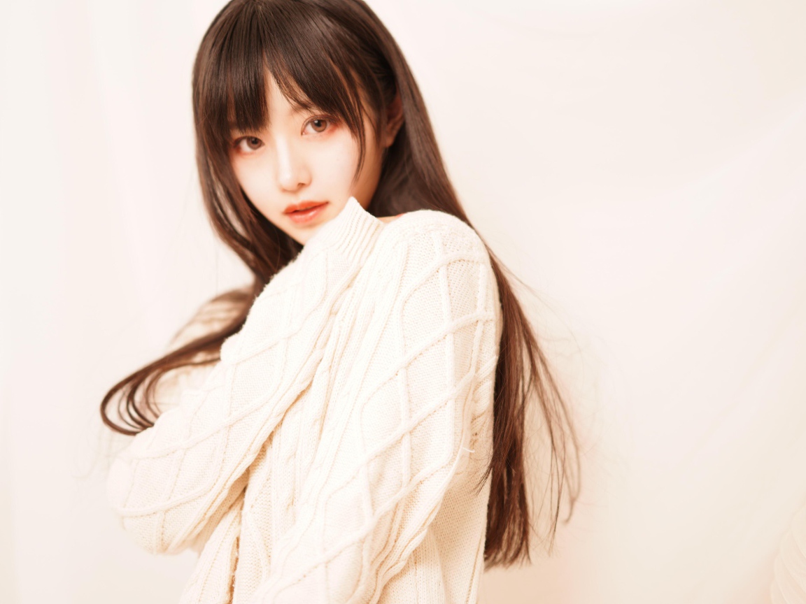 Милая азиатка в белом свитере на розовом фоне