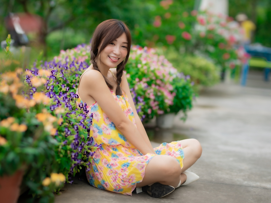 Смешная девушка азиатка в платье сидит на земле