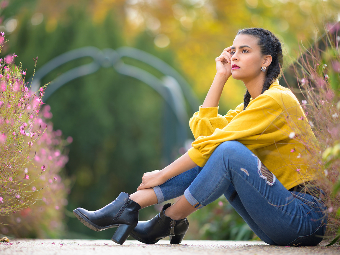 Девушка в джинсах сидит на земле 