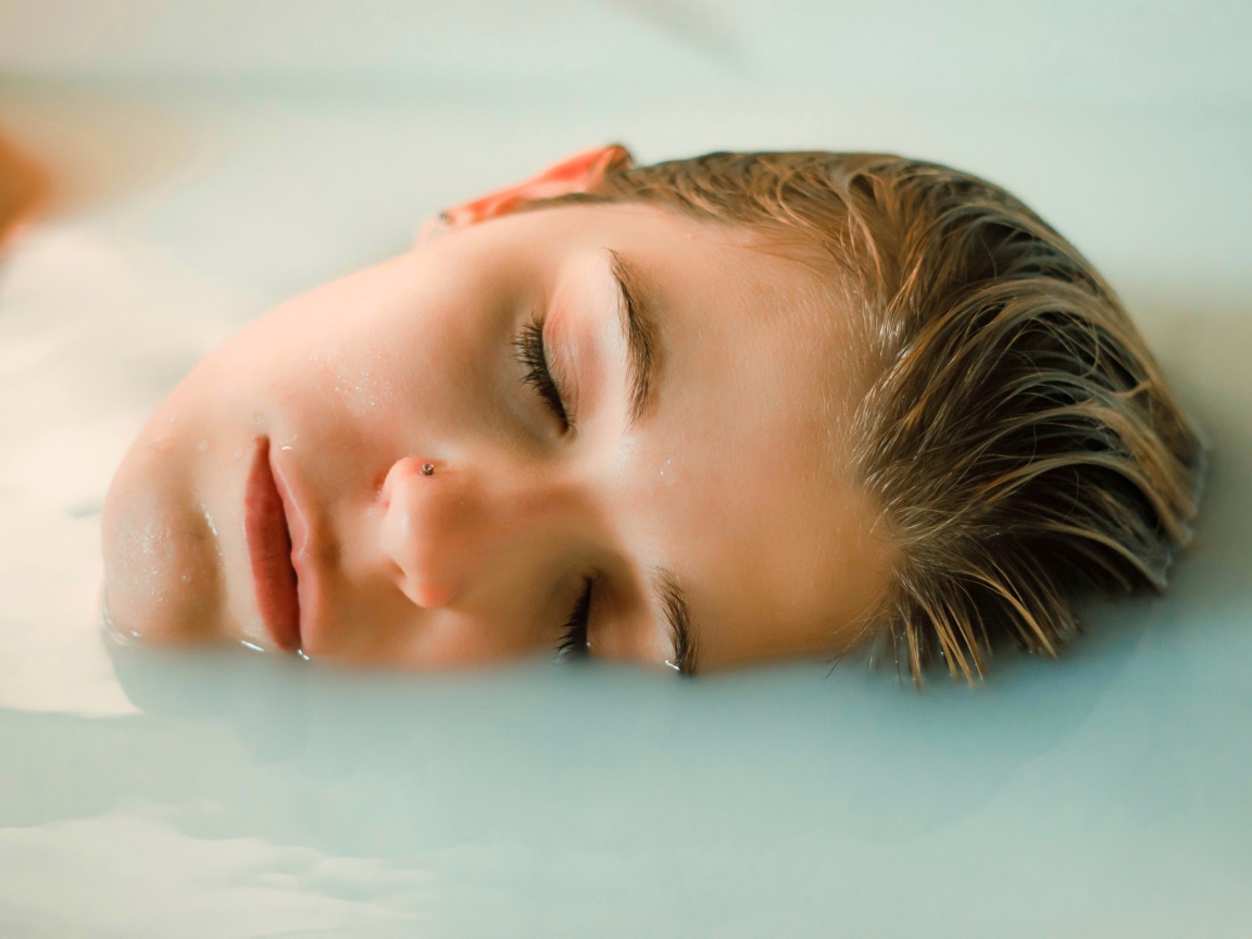 Девушка лежит с закрытыми глазами в ванной