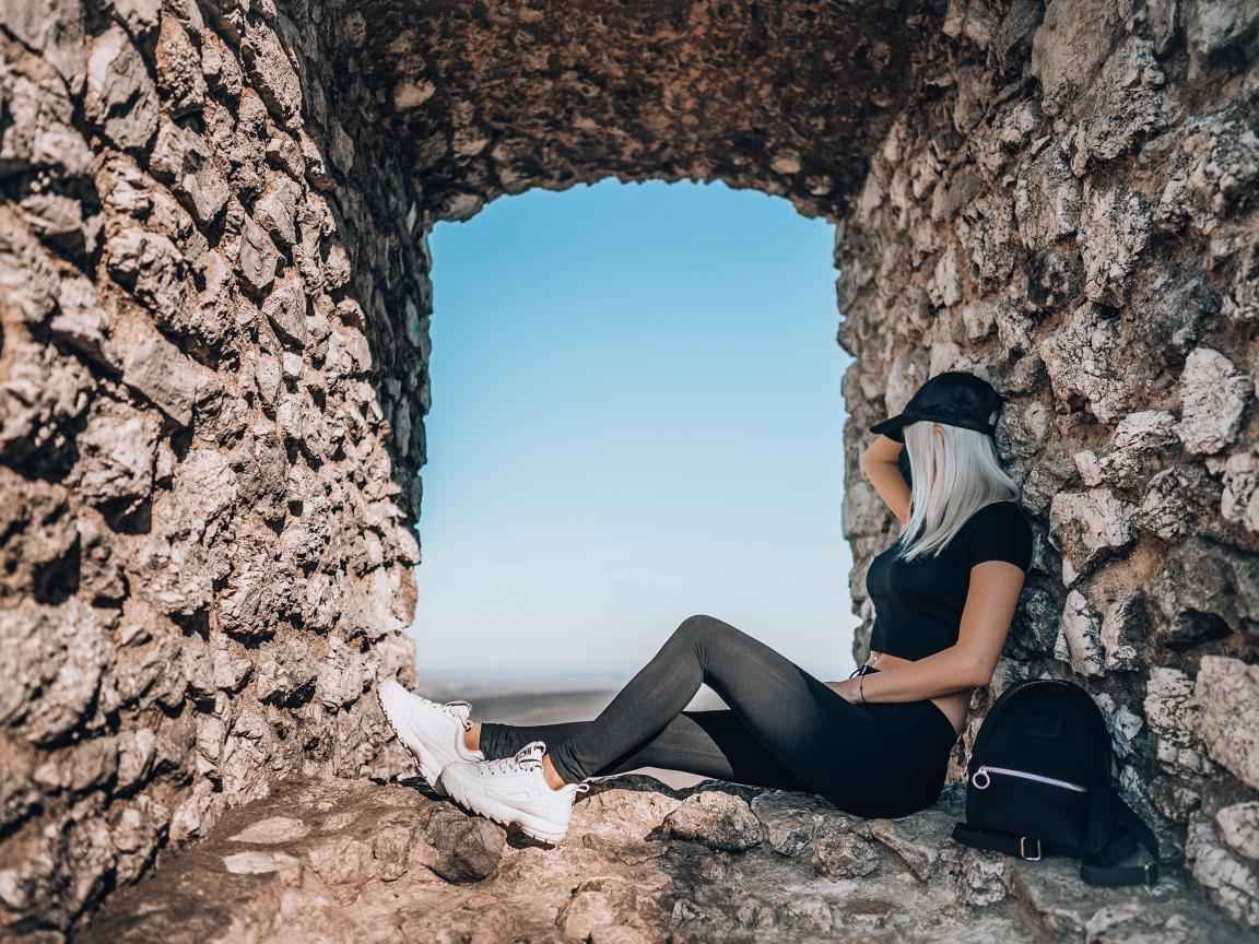 Девушка сидит в окне старого здания 