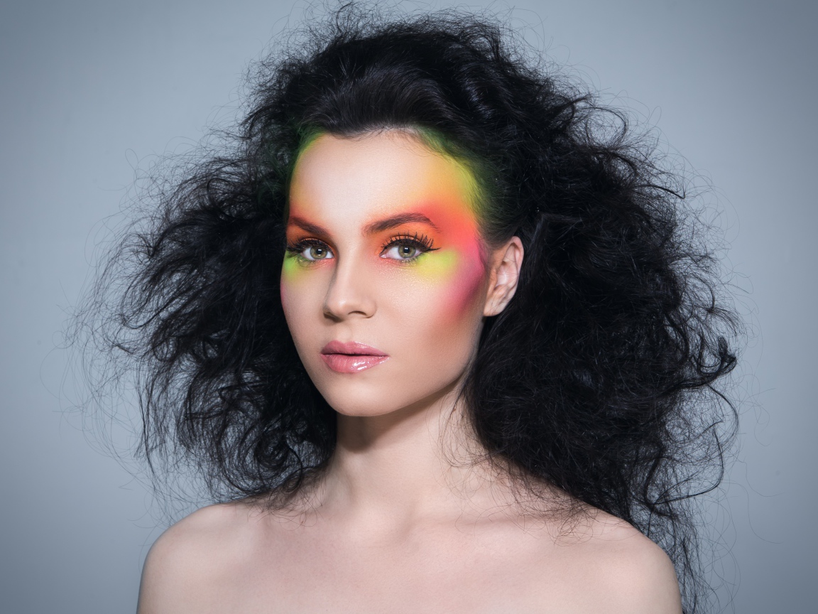 Девушка с начесом на волосах с ярким макияжем на сером фоне