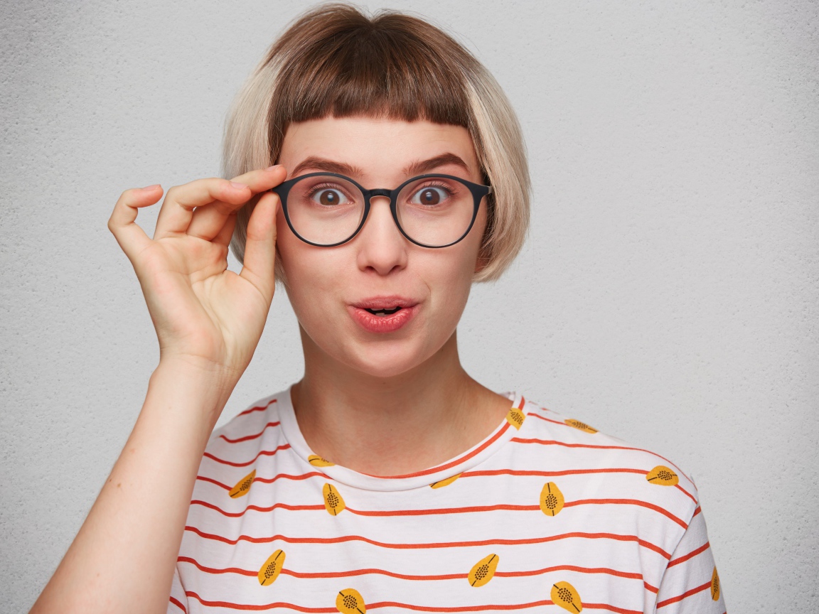 Девушка с короткой стрижкой поправляет очки 