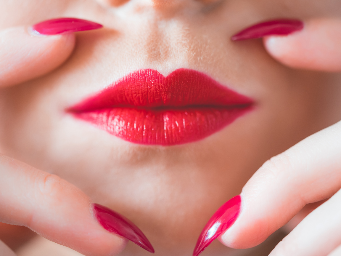 Руки с длинными красными ногтями у губ