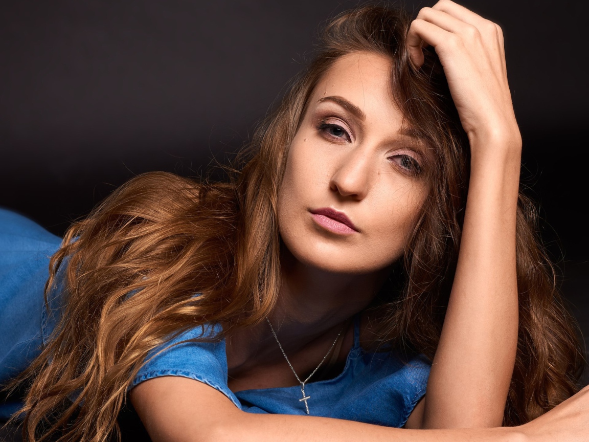 Длинноволосая шатенка лежит на полу в голубом платье 