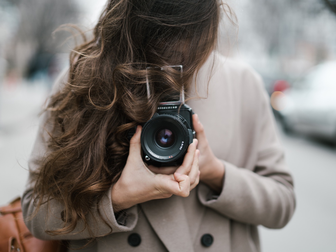 Длинноволосая девушка с фотоаппаратом в руках 