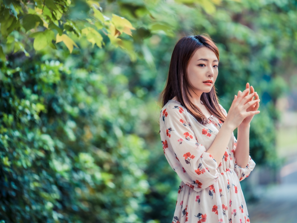 Грустная девушка азиатка в платье в парке
