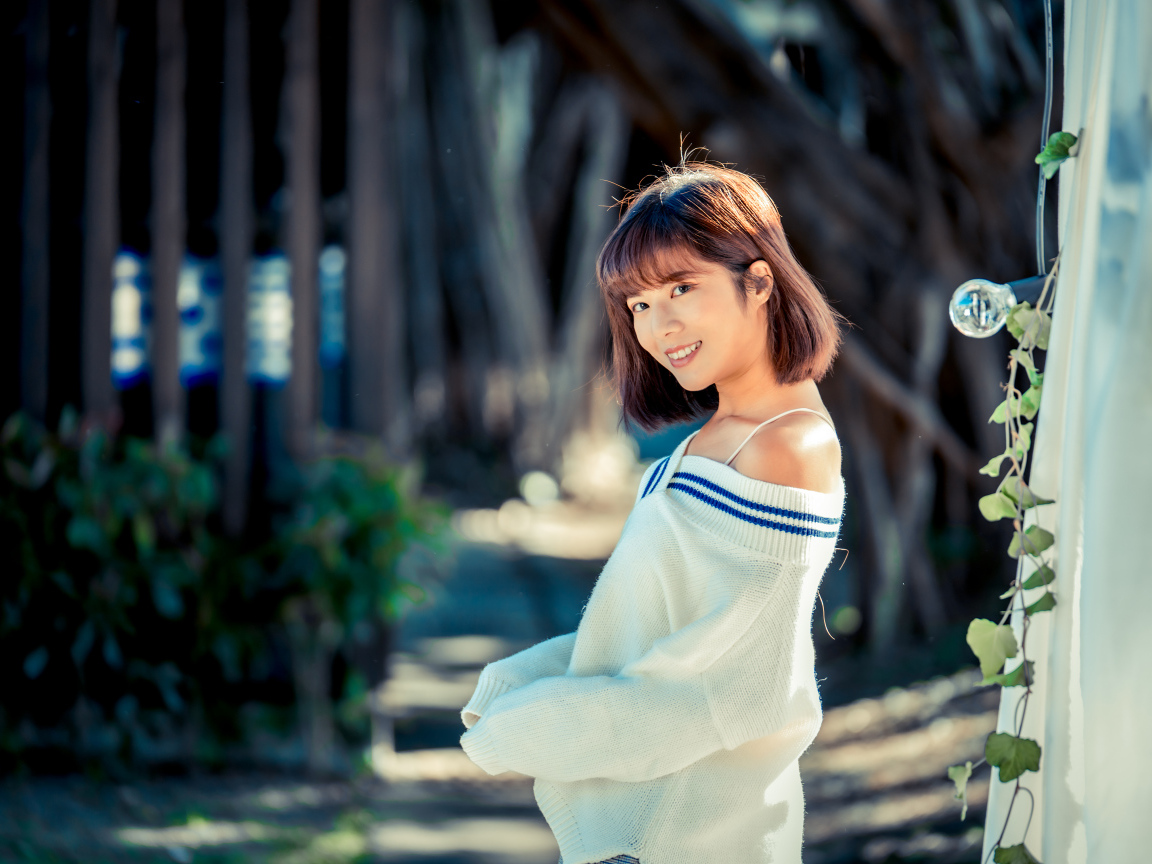 Улыбающаяся девушка азиатка в белом свитере 