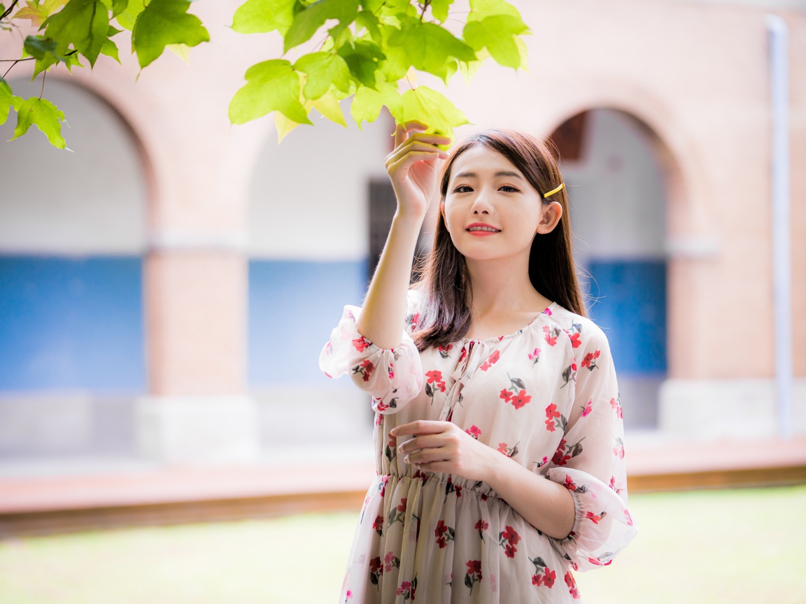 Улыбающаяся девушка в платье у дерева 