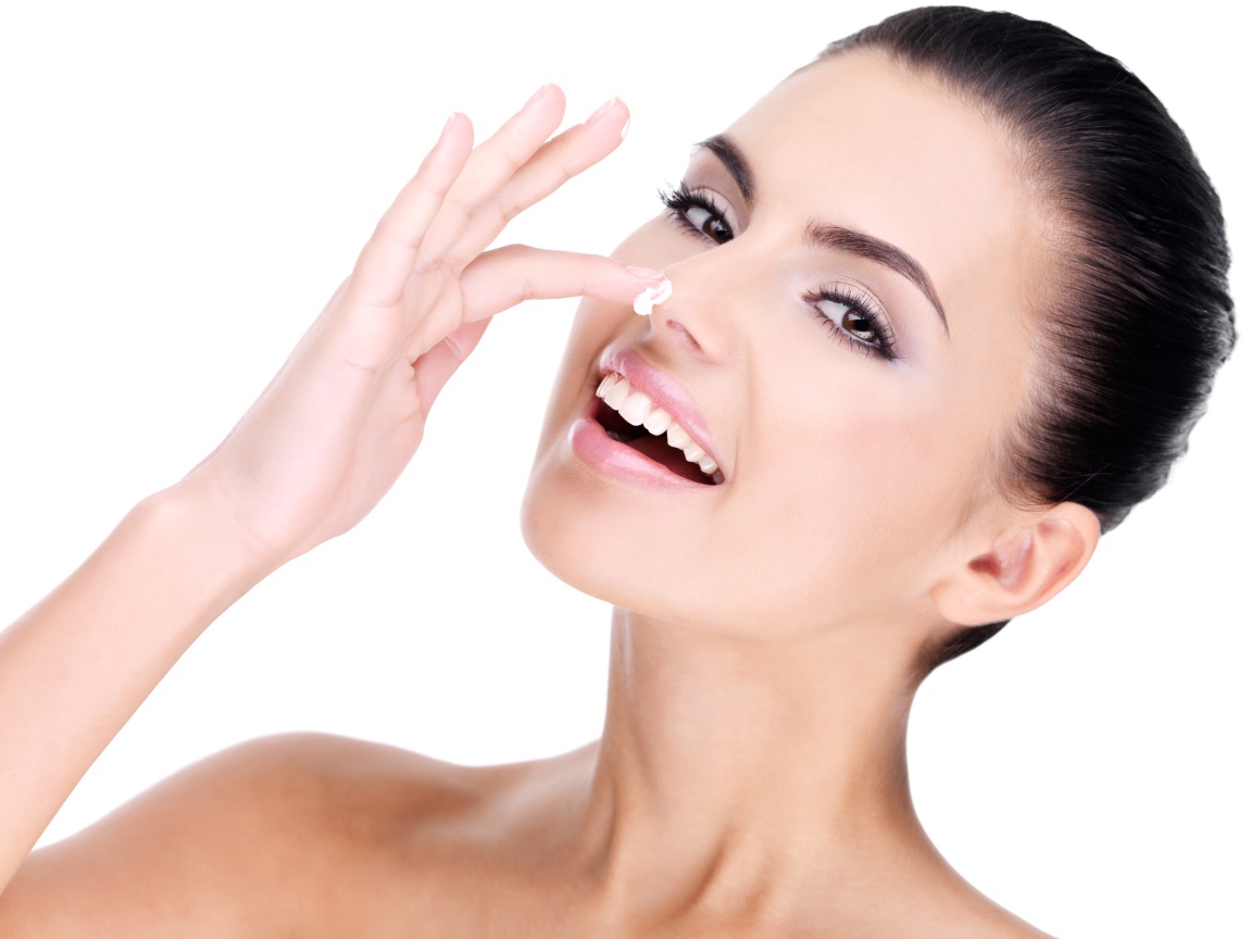 Улыбающаяся девушка мажет крем на нос 