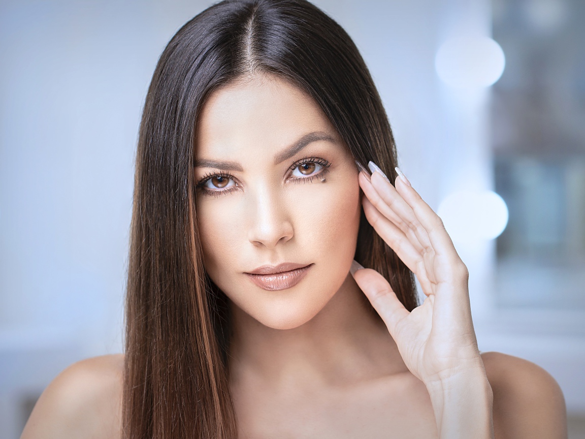 Стильная кареглазая длинноволосая брюнетка с рукой у лица