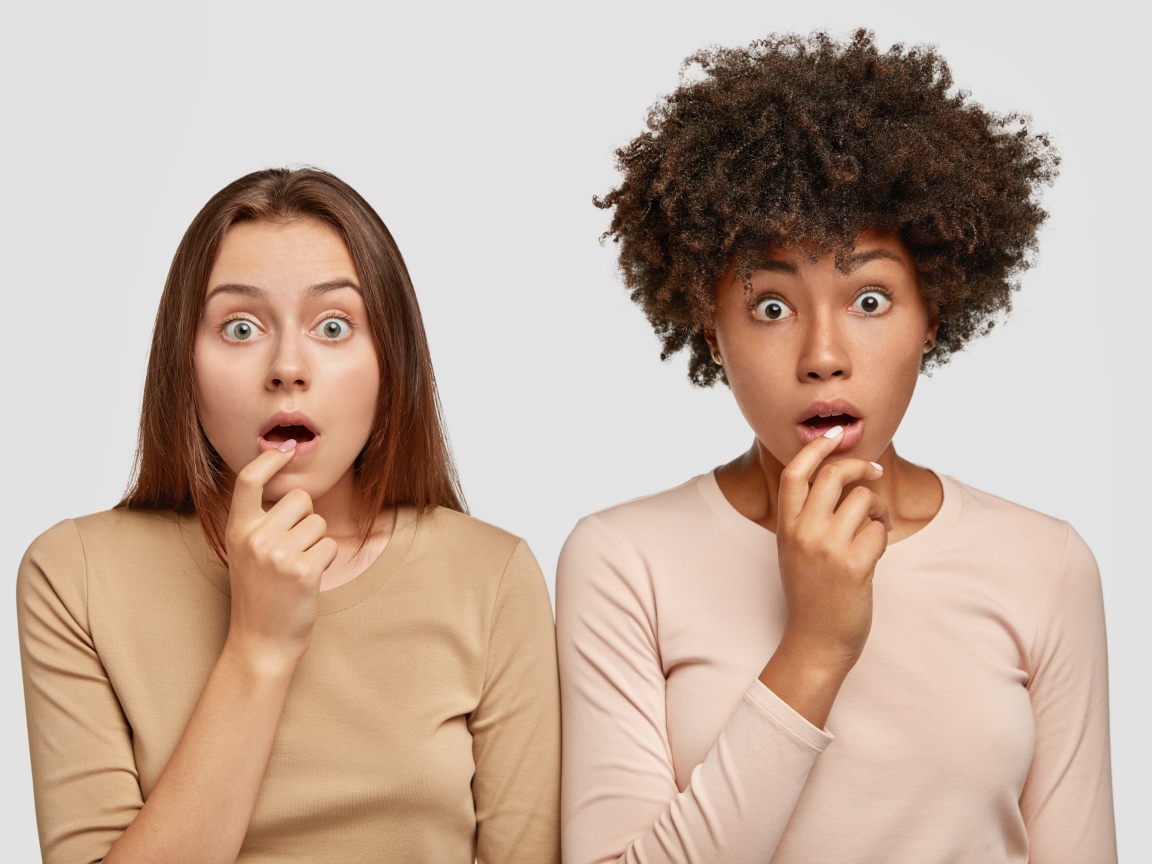 Две удивленные девушки на сером фоне 