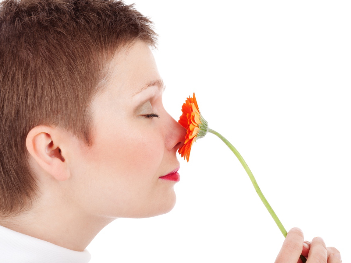 Женщина с закрытыми глазами с цветком герберы в руке