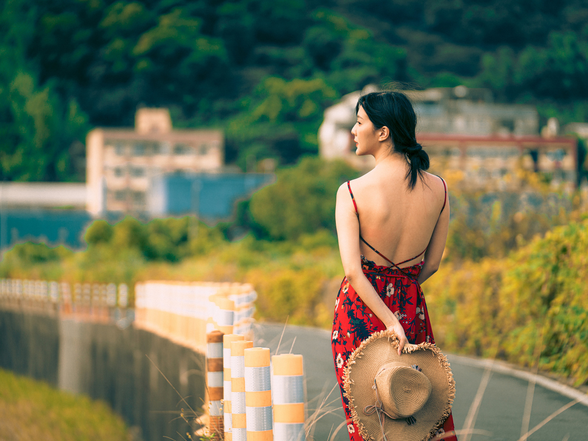 Молодая девушка азиатка в сарафане со шляпой в руке 