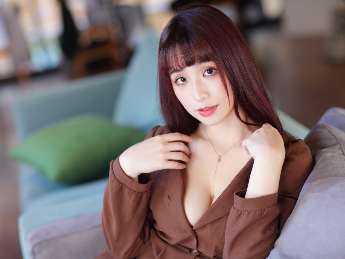 Молодая азиатка сидит на диване 