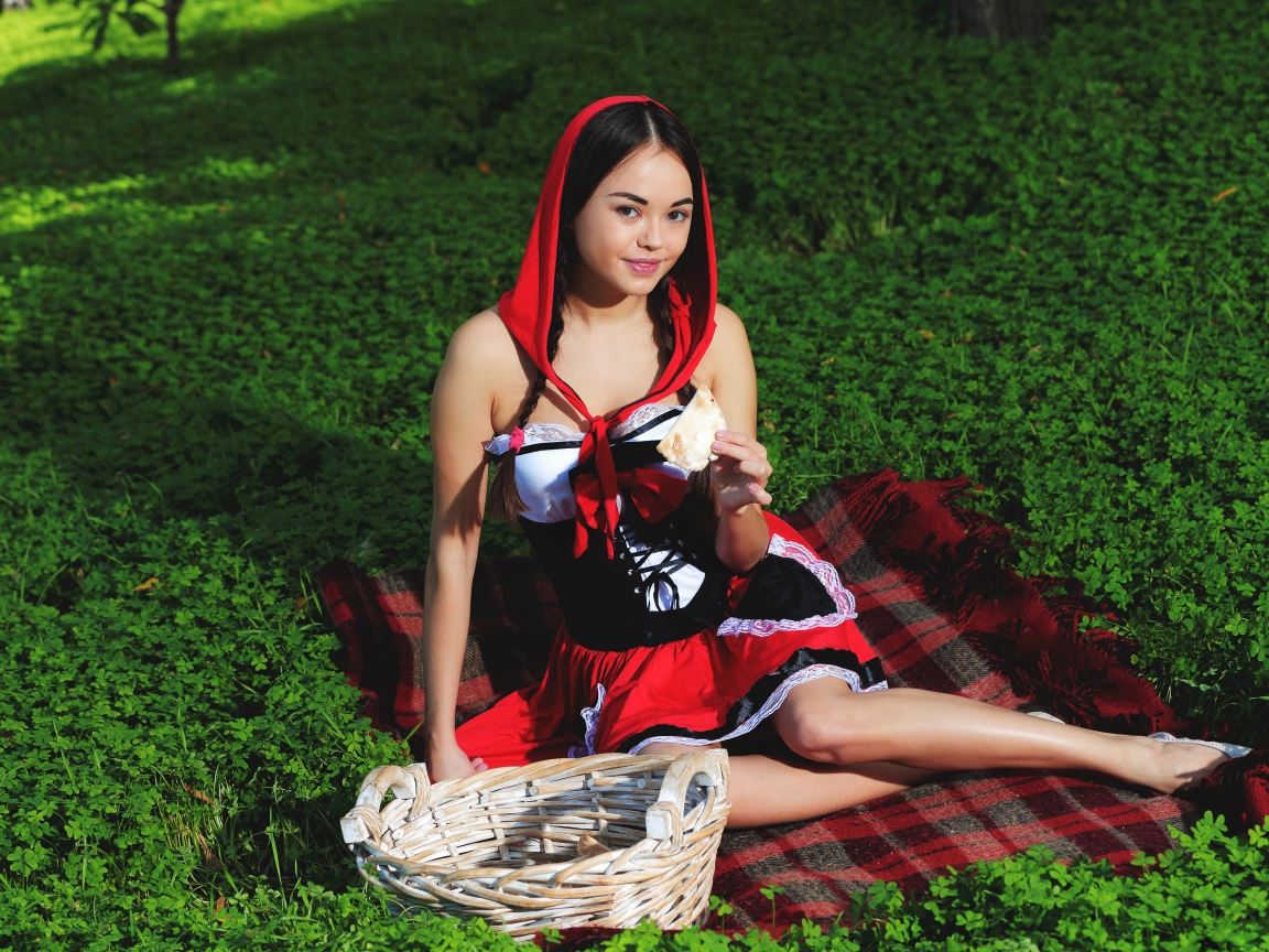 Молодая девушка в костюме сидит на траве, косплей