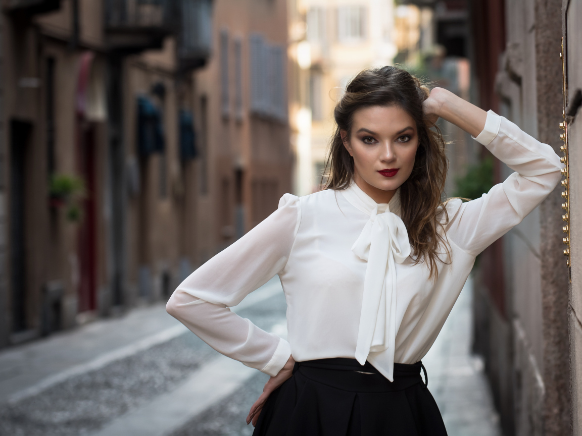 Молодая девушка в белой рубашке у стены