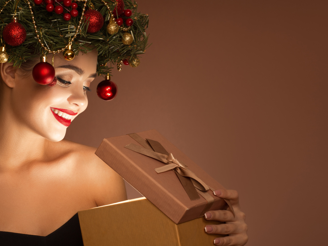 Красивая девушка с рождественским венком на голове с подарком