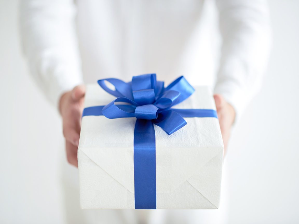 Подарок с голубым бантом в руках 