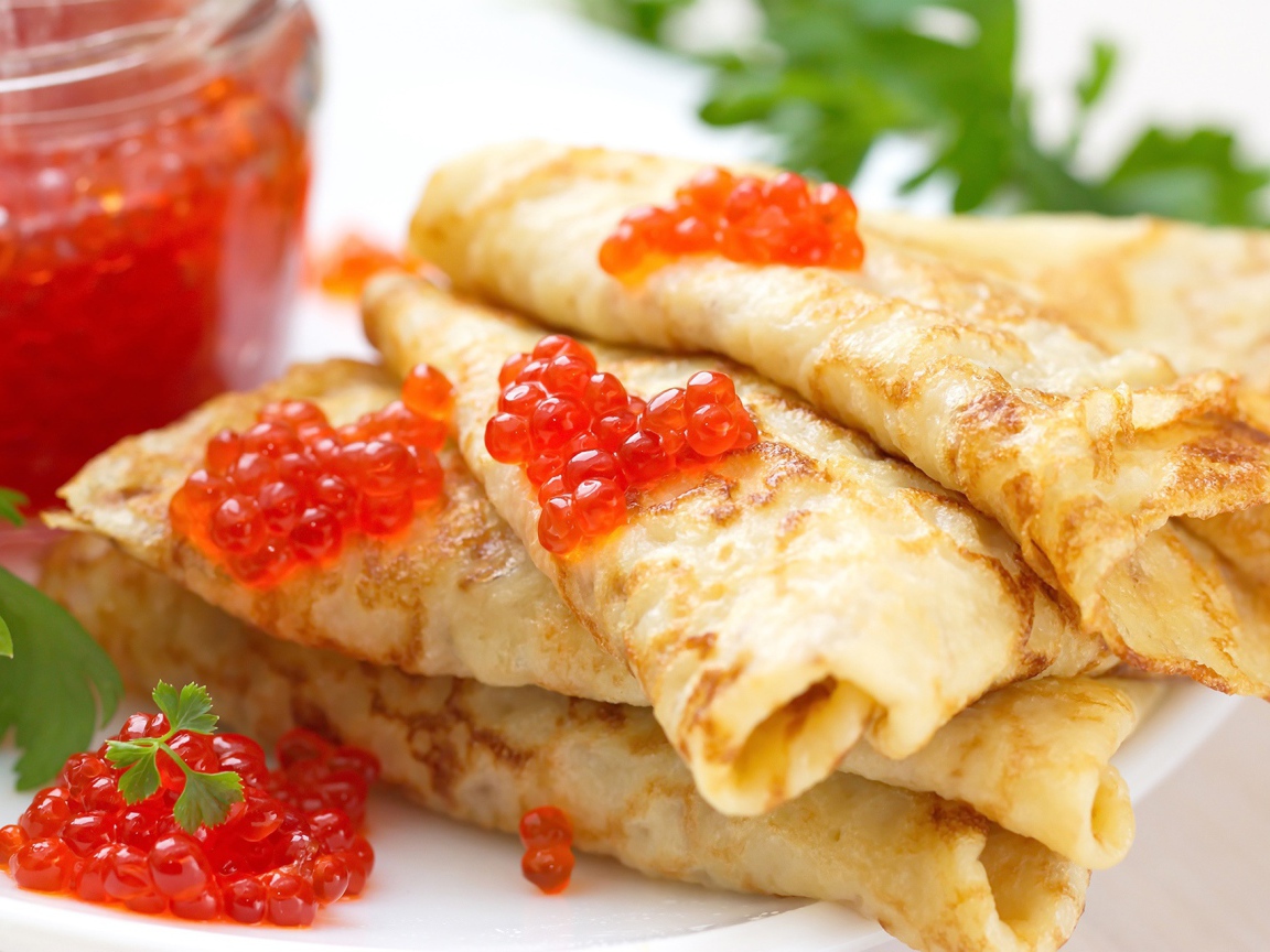 Аппетитные тонкие блины с красной икрой на тарелке с петрушкой угощение на Масленицу