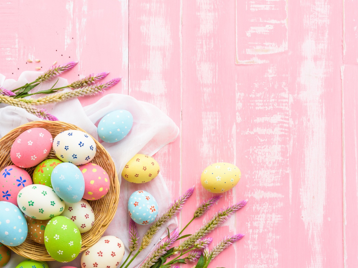 Корзина с крашеными яйцами на розовом фоне