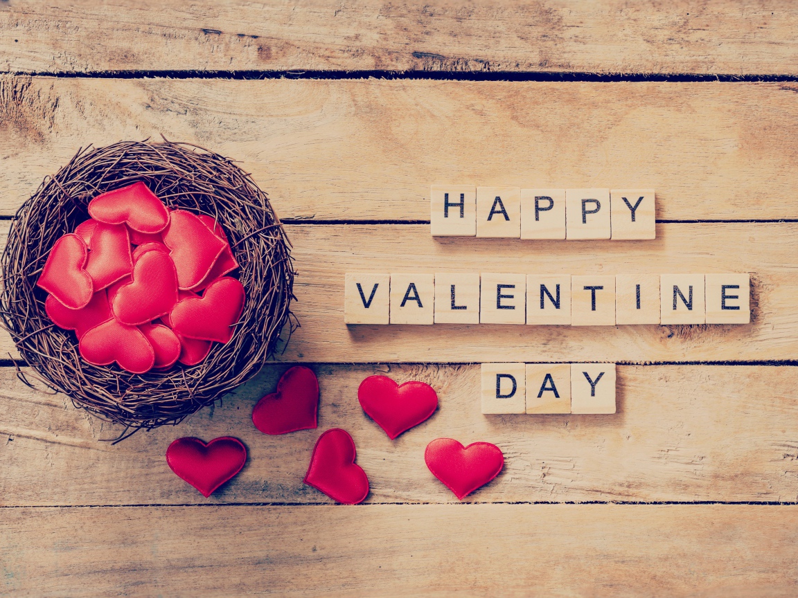 Кубики и гнездо с сердечками на деревянном столе на День Святого Валентина