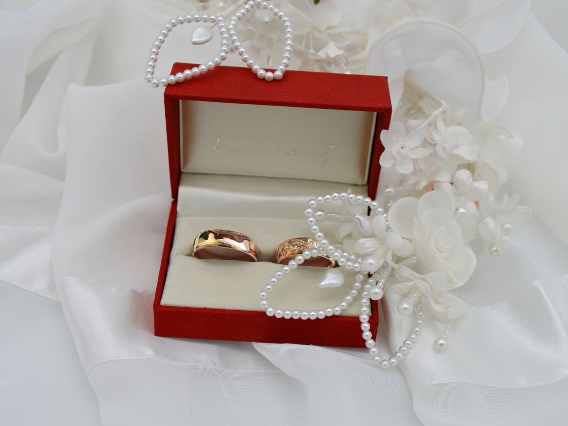 Золотые обручальные кольца в красной коробочке с украшениями