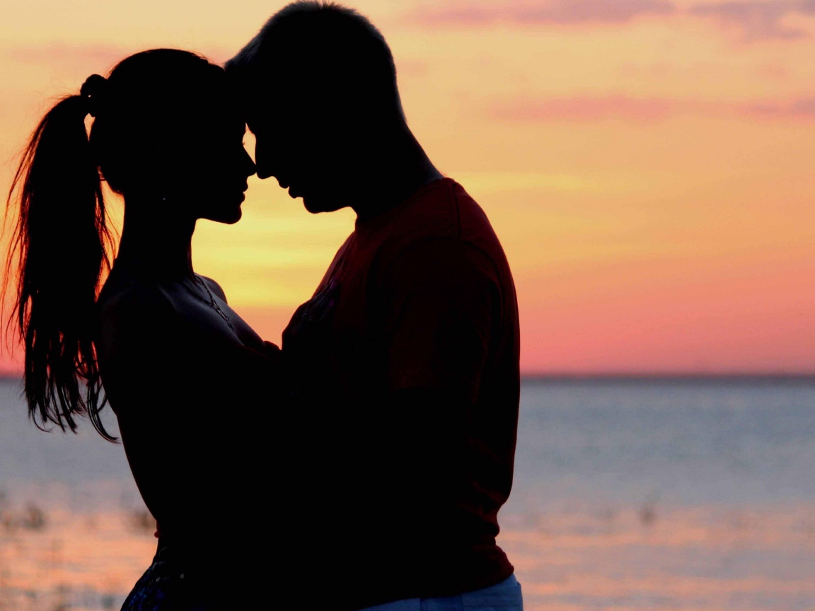 Влюбленная пара на фоне моря в сумерках 