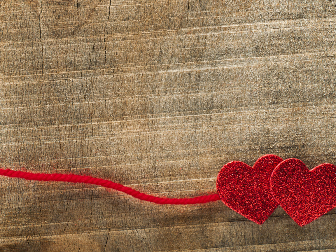 Два красных сердца со шнурком на деревянном фоне