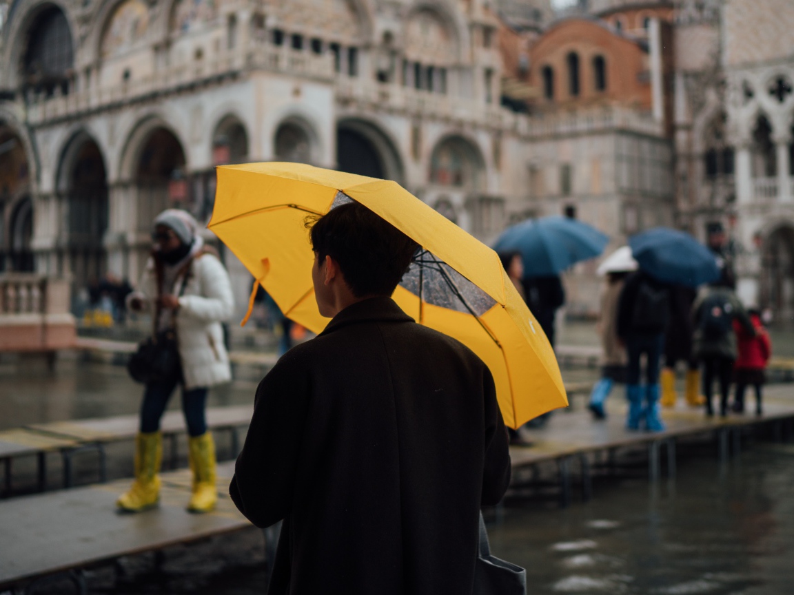 Мужчина с желтым зонтом в городе 