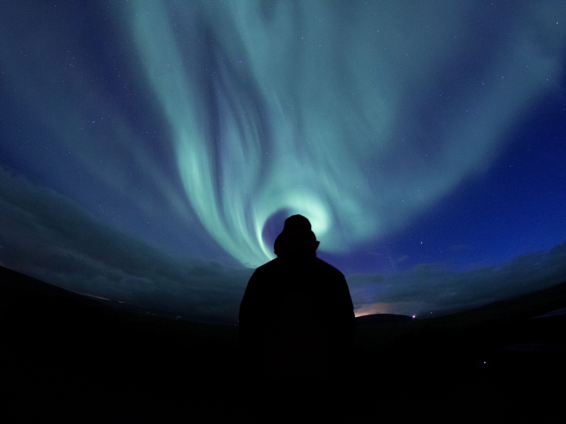 Silhouette of a man on a background of the sky with aurora