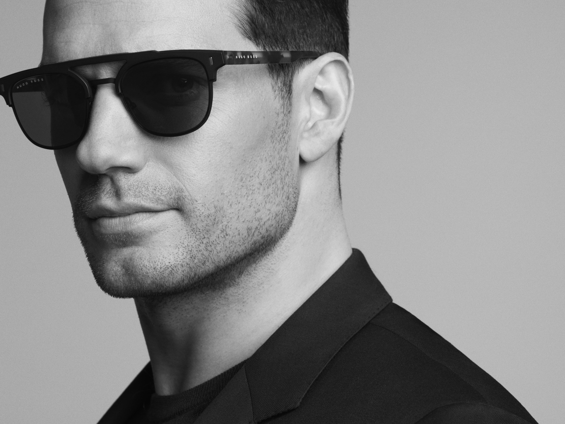 Актер Генри Кавилл в черных очках на сером фоне