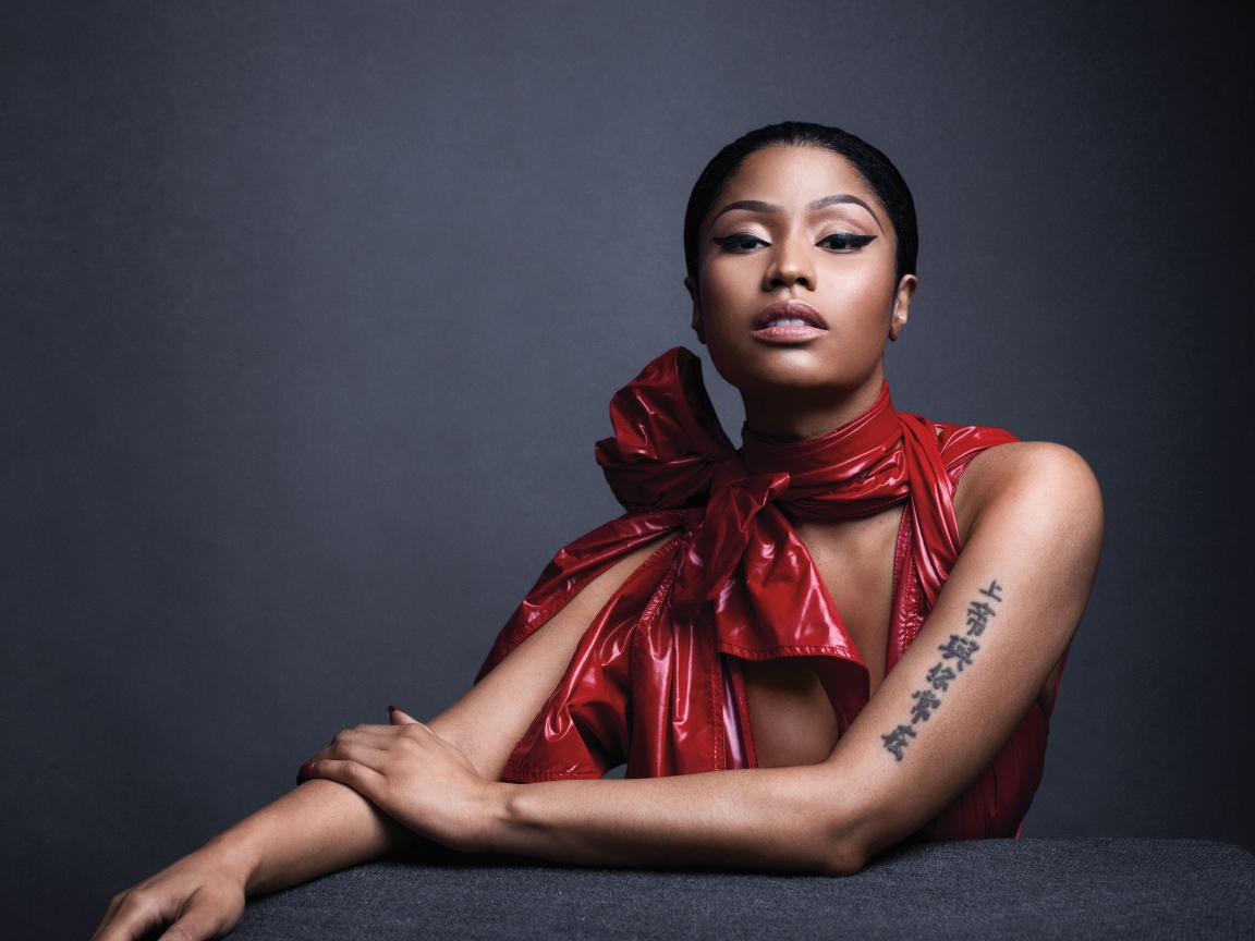Американская певица, рэпер Ники Минаж  в красном наряде на сером фоне
