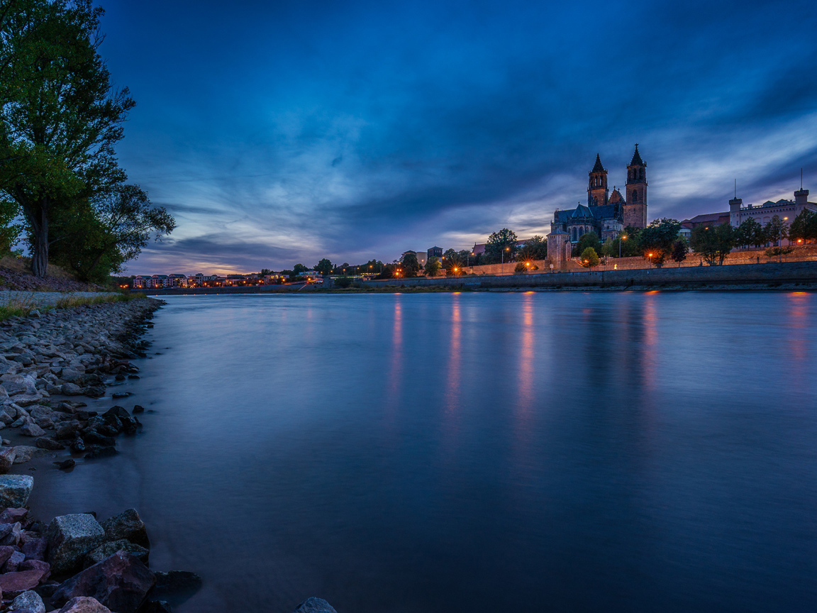 Замок у реки на фоне неба в сумерках 