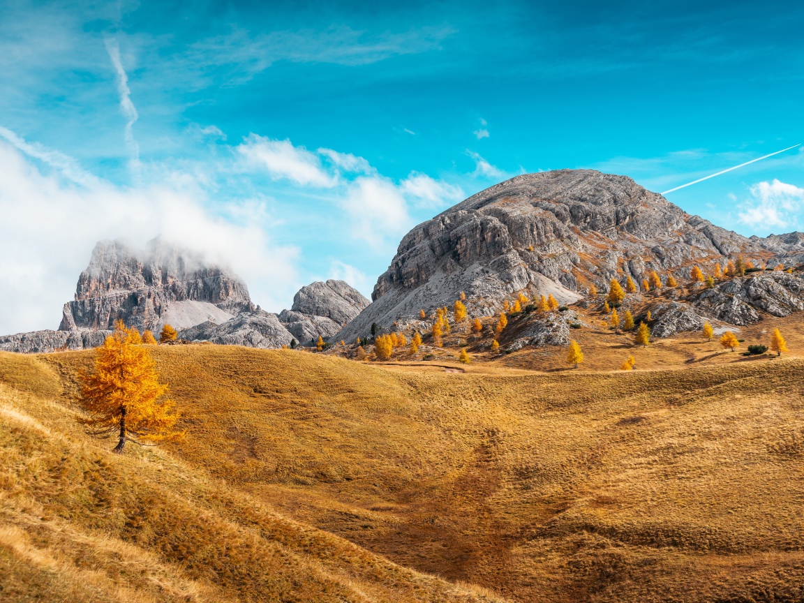 Холмы с сухой травой у гор под голубым небом