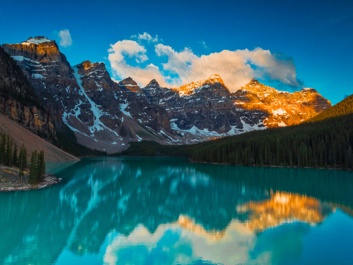 Солнце над высокими горами у голубого озера