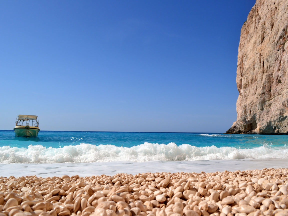 Красивая голубая вода с белыми волнами на пляже с галькой 