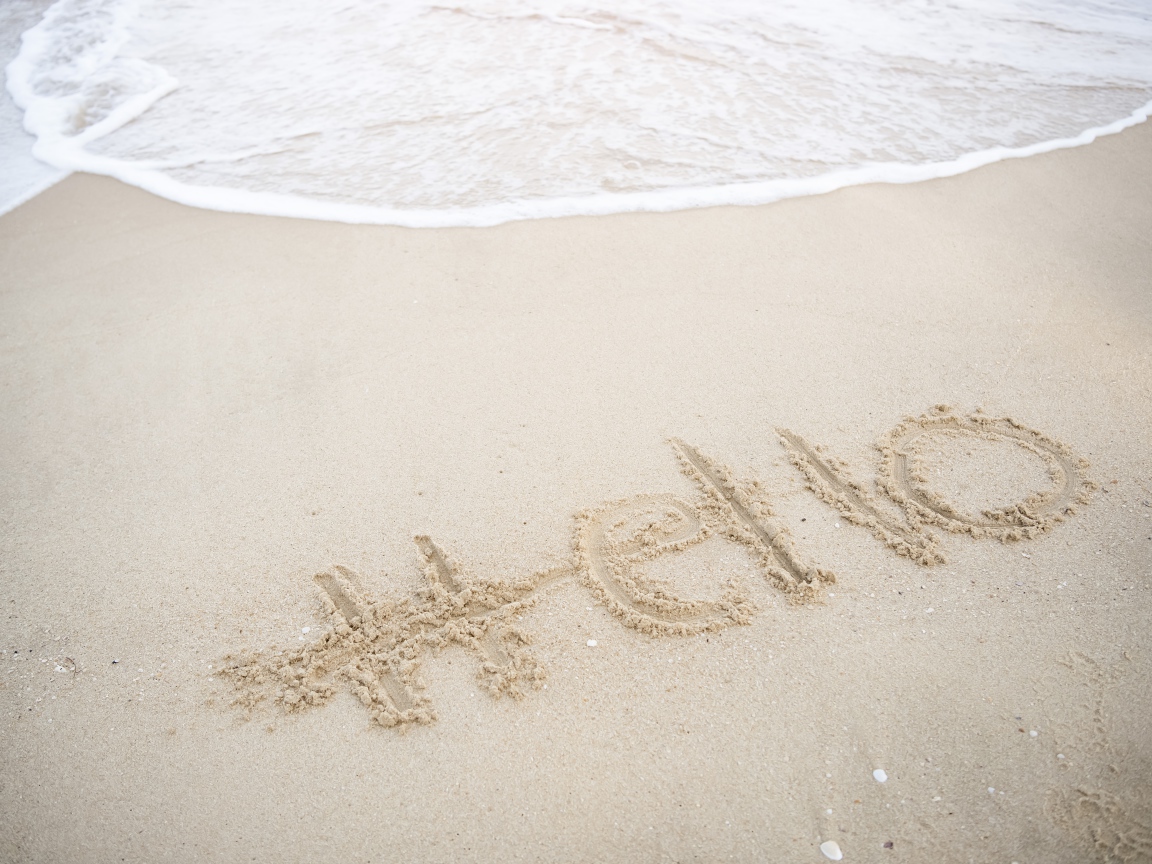 Надпись Hello на мокром песке у моря летом 