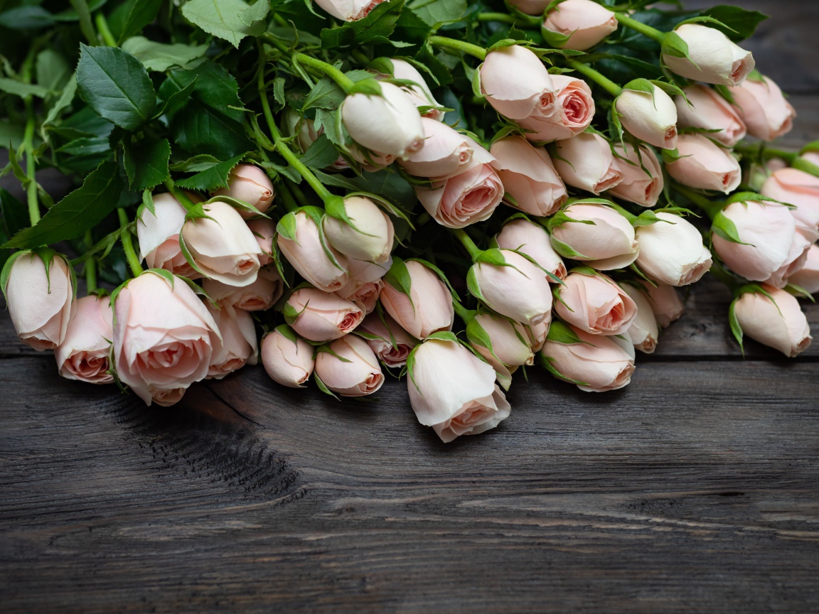 Большой букет розовых роз на деревянном столе 