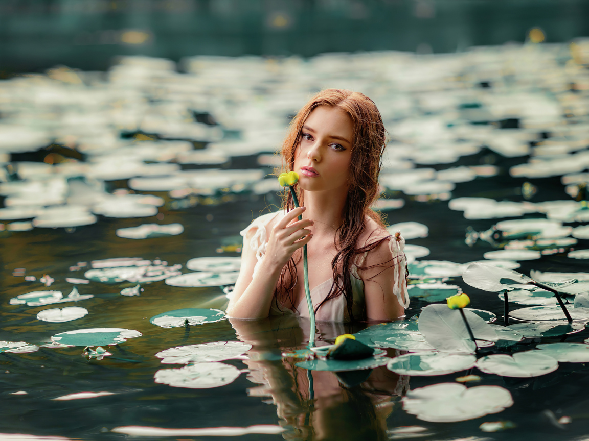 Красивая молодая девушка с водяными лилиями в пруду