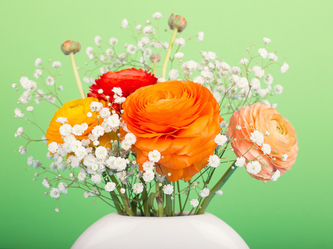 Букет разноцветных лютиков в белыми цветами в вазе на зеленом фоне