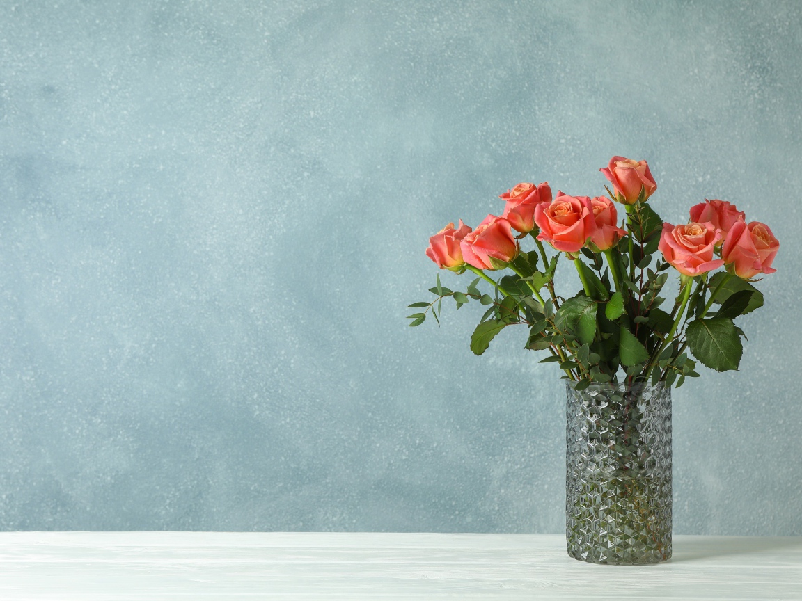 Букет роз в стеклянной вазе на сером фоне